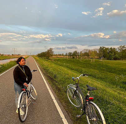 Anusha standing with a bicycle on a country road